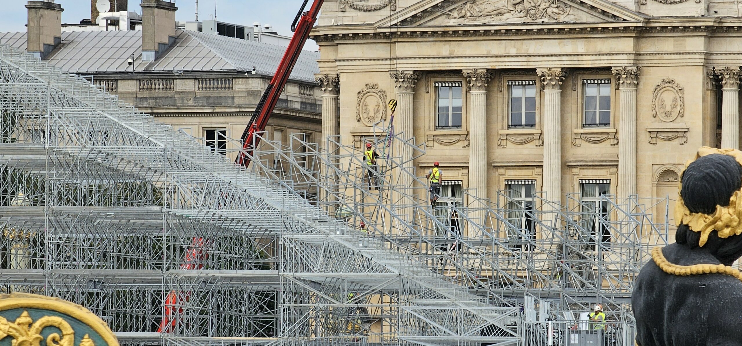 Photo de cordiste assurant le montage d'une tribune des jeux olympiques sur la place de la Concorde à Paris.